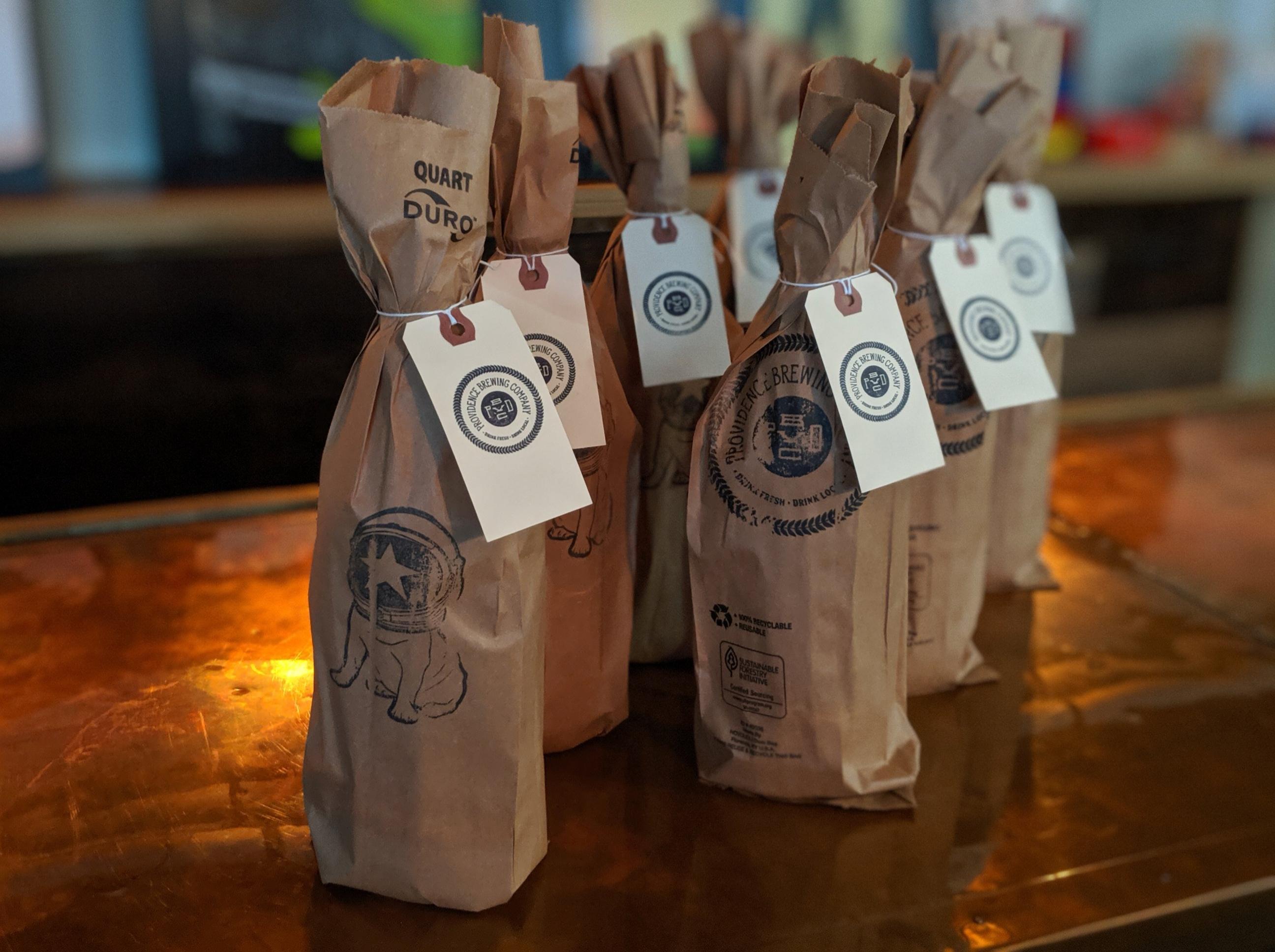 Providence Brewing Company anniversary bottles wrapped in stamped brown paper bags with hang-tags